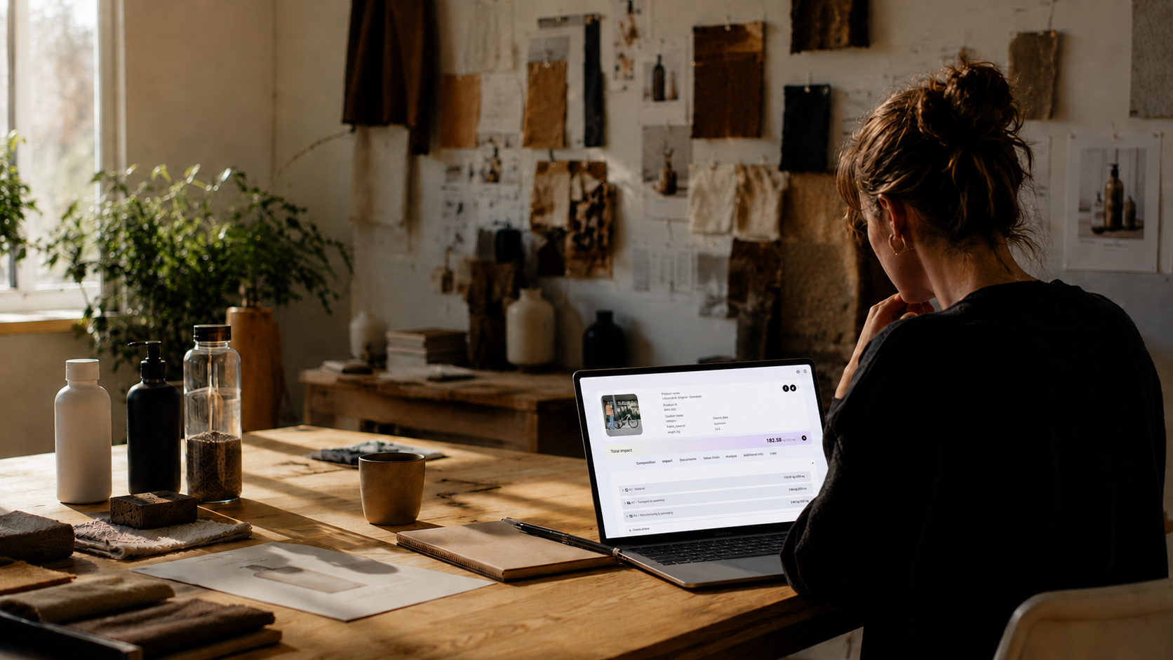 Designer reviewing an EasyLCA product impact report at a sunlit workshop desk